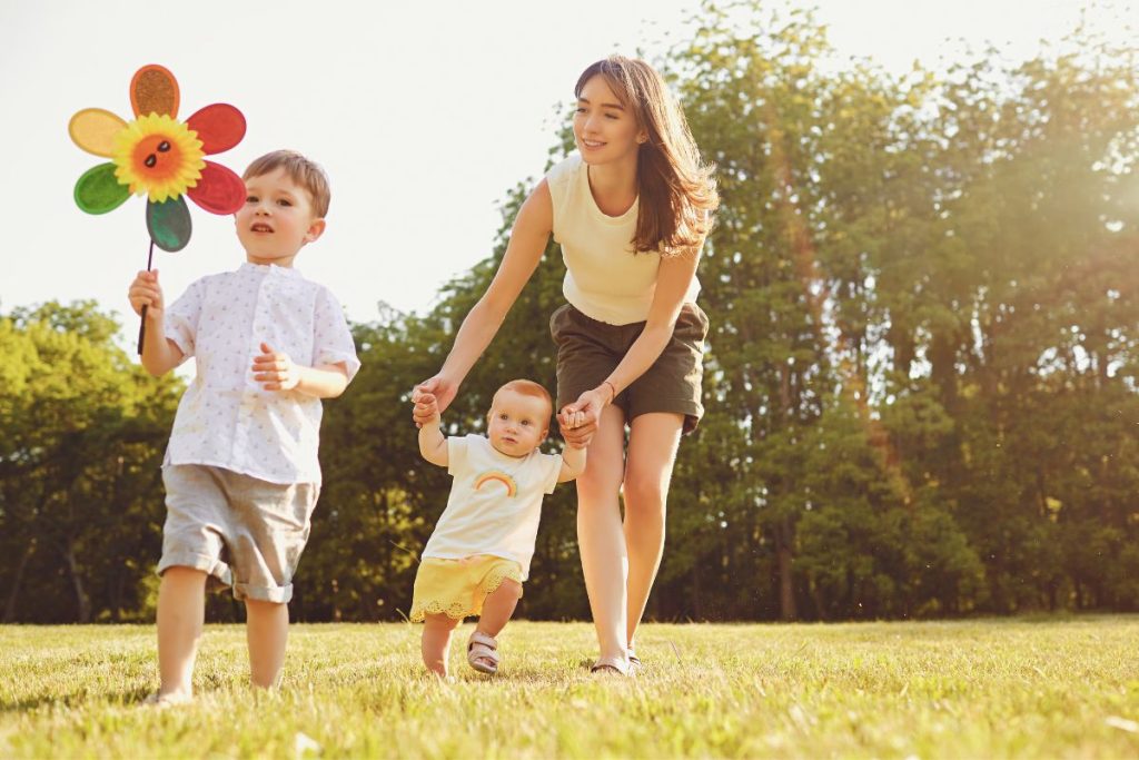 mother and two kids walking in the park on a sunny day to get some vitamin d and prevent the deficiency